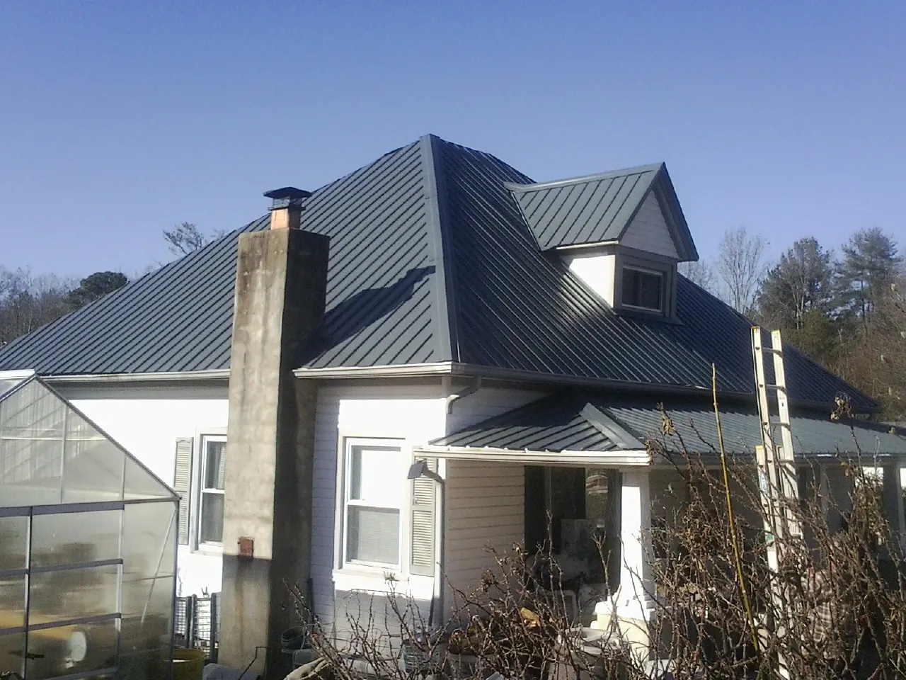 Dark blue standing seam metal roof on a white farmhouse with dormer — Slate & Tile Roof Repair by Roofing Brothers in Cache