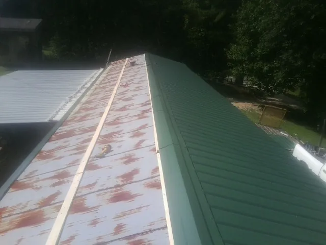 Old rusted panels beside newly installed green metal roofing — Wind Damage Roof Repair by Roofing Brothers in Cache