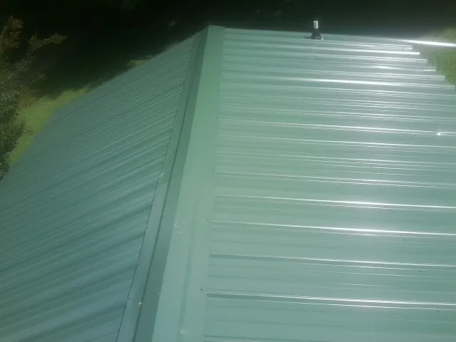 New green metal panels meeting at the ridge of a roof — Flat Roof Repair work by our crew in Cache