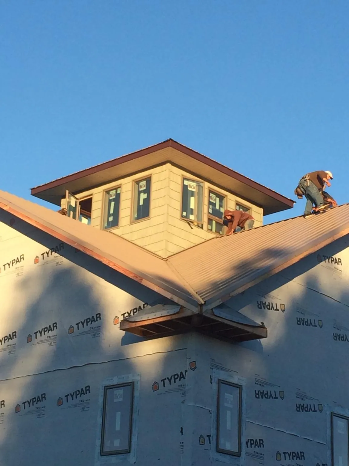 Roofers working around a rooftop cupola on a new metal roof at sunset — Roof Waterproofing in Cache by Roofing Brothers
